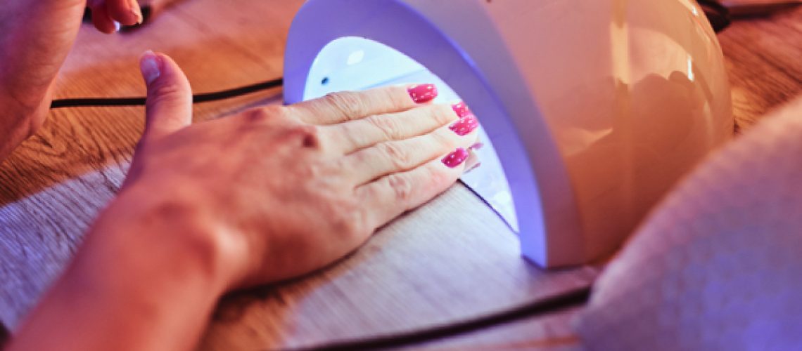 Client-at-manicure-salon-dryes-gel-nails-in-UV-light-1.jpg