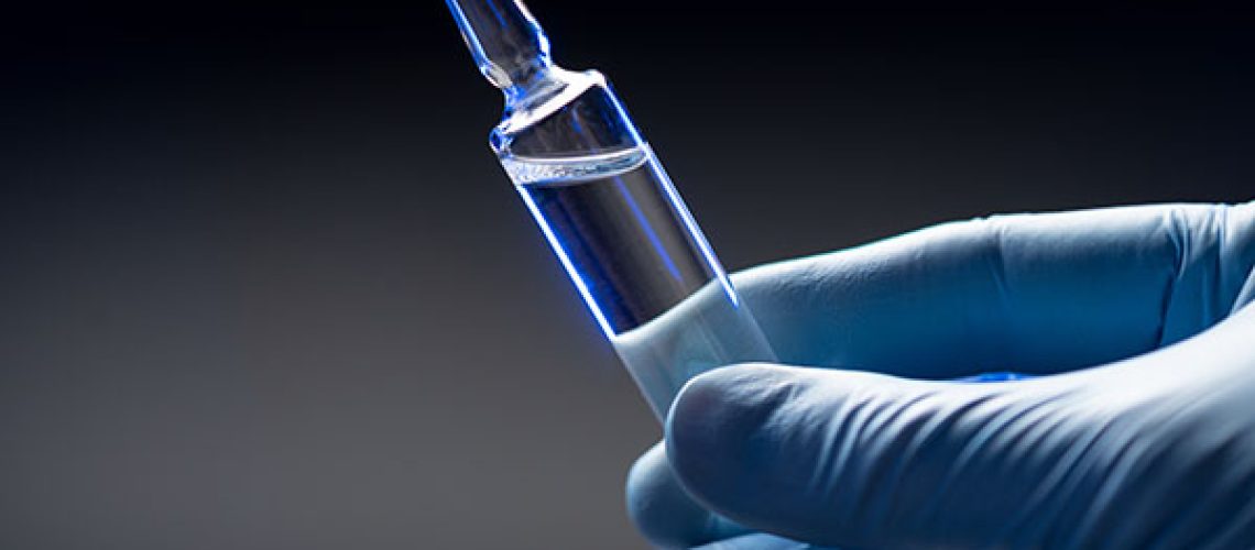 Hand-in-blue-medical-gloves-holds-an-ampoule.jpeg