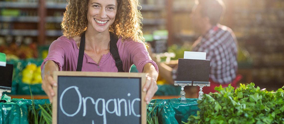 Smiling-Staff-Holding-Organic-Sign-Board-In-Organic-Section.jpg